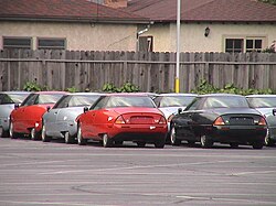 Red, light blue and dark green EV1s at a facility, awaiting to be crushed