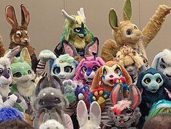 A group of people wearing rabbit fursuits, varying from very realistic to very cartoony