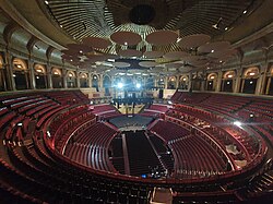 Interior of the Royal Albert Hall, showing the stage, seating tiers, and acoustic diffusers beneath the dome.