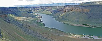 Wide view over a river valley surrounded by cliffs and shrub land