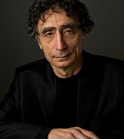 close-up of Gabor Maté wearing a black sport jacket, looking directly at the camera