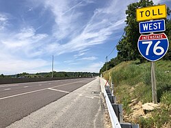 Two empty lanes of a highway, with wispy clouds