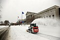 Skid loader clearing snow with snow blower attachment