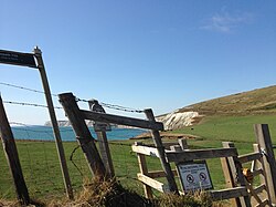 Skewing in a photograph taken from a car moving at 80 km/h (50 mph). Objects in the foreground, such as the fence and gate, have become skewed, while more distant objects in the background, such as the cliff, appear normal.