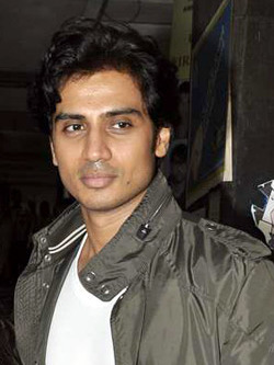 Shiv Panditt in a white T-shirt and camo jacket, looking away from the camera