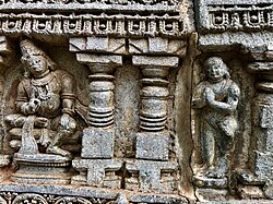 Hindu god Kubera on the left with a person in Añjali Mudrā (13th century Chennakesava Temple, Somanathapura, Karnataka).