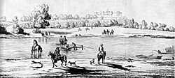 A small wooden raft in the middle of a river which runs through a flat rural landscape.