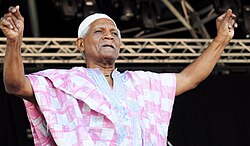 Elderly African-American man in pink tunic on outdoor stage