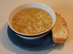 a bowl of brown coloured soup with egg white flecks