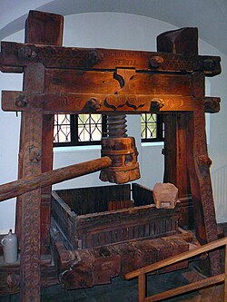 Large wooden screw press with vertical timbers and central screw