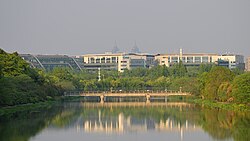 A couple of mid-height buildings in front of a bridge crossing a river