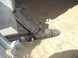 A wye joining a perforated and a solid corrugated pipe to a buried solid outlet