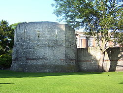 Ancient stone wall and roofless tower with narrow windows.
