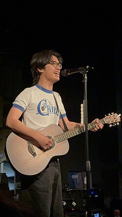 Mico singing something in a microphone with a guitar