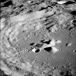 A gray, 9feature is a circular ringed structure with high walled sides and a lower central peak: the entire surface out to the horizon is filled with similar structures that are smaller and overlapping.