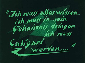 A black screen with green faded shapes in the background, and green words in German language written in angled block letters in the foreground.