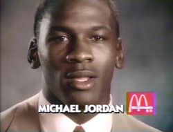 Michael Jordan in tan suit against a gray background. At the foreground is the text saying "Michael Jordan" and the McDonald's logo.