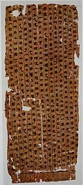 A vertical tattered silk scroll displaying Chinese characters written with ink