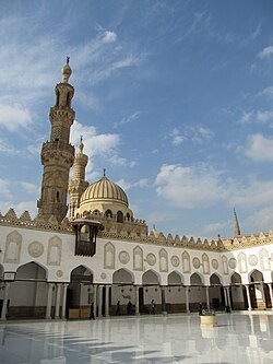 View inside the main courtyard of al-Azhar Mosque. A pointed dome and a minaret tower rise above.