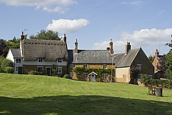 A thatched house adjoining other traditional ironstone buildings