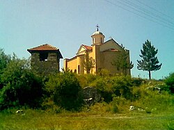 A bright yellow church sits far from the camera, with grass and a small verge occluding some of the bottom.