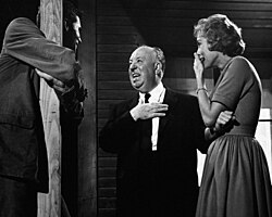 Two men and one woman laughing together on a film set.
