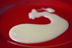 A puddle of white chocolate ganache on a red plate