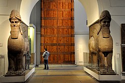 Pair of Assyrian lamassu sculptures built into an arched doorway, displayed in British Museum