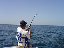 A man fishing off of a boat into the deep blue sea