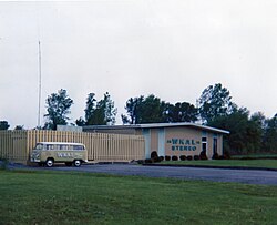 The combined WKAL studio and transmitter facility, South Jay Street, Rome, New York; Spring of 1974. During the previous year, FM Stereo service had been initiated, simulcasting AM programming. The station's building markings were updated to advertise the change. To the left the station's VW Bus can be seen which was utilized during this period for promotional events.