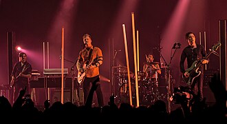 Queens of the Stone Age in 2017. Left to right: Dean Fertita, Josh Homme, Jon Theodore, and Michael Shuman. Not pictured: Troy Van Leeuwen.