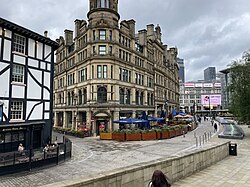 A partial view of the previous image but now a modern colour photograph; the building is a limestone facade and in the central tower there is a sign that says "CORN / EXCH / ANGE"