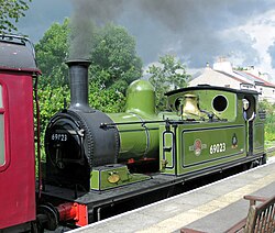 Green side tank locomotive at a station platform
