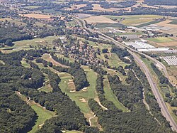 Aerial photograph showing fairways, greens, bunkers, and surrounding landscape at a French golf course near the A40 motorway.