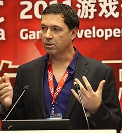 An image of Brian Fargo. He is standing behind a podium.