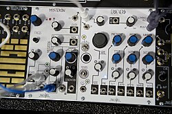 A white panel that is covered with various blue and white dials, wires and empty sockets