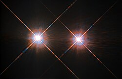 Two white disks side by side, each with coloured fringes and prominent diffraction spikes