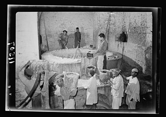 A soap factory in Nablus. The boiling pot liquid soap being carried to stock room. By the Matson Photo Service. c. 1940