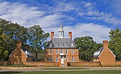 A three-story red brick colonial-style hall and its left and right wings during summer.