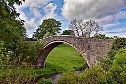 Stone built arched bridge over a small river in a rural setting