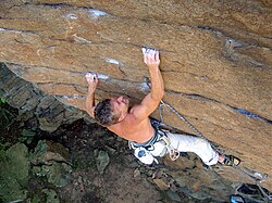 A climber using the crimping and edging technique on an outdoor rock face