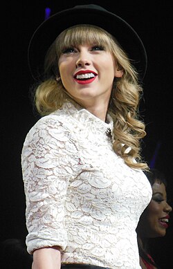 Swift in a white laced oxford shirt and black fedora hat