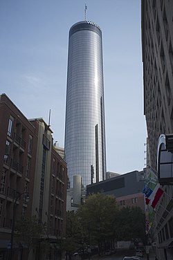 A blue glass cylindrical building topped with a spire
