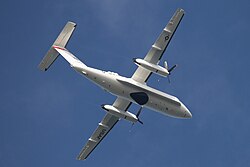 A lower right rear quarter view of a white aircraft in flight.