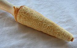 Krumkake just off the hot iron, being shaped on a conical rolling pin