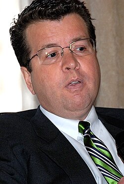 Photograph of Neil Cavuto, an American television news anchor, wearing glasses, a dark suit, and a striped tie.