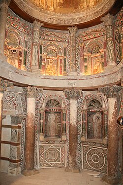 Ancient church interior with ornate stone arches, columns and religious frescoes on walls