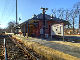 A single-story brick railway station building and a low-level side platform next to a single track