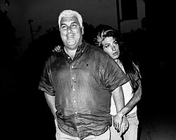 Black-and-white image of Mitch in the foreground, smiling and looking at the camera; behind him is Winehouse, leaning on his shoulder