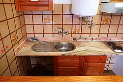Rustic style tiled kitchen sink area in a rental apartment in Portugal. Stainless steel kitchen sink. Marble countertop.